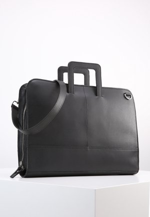 Czarna skórzana aktówka o gładkiej fakturze, wyposażona w dwie górne rączki, odpinany pasek na ramię oraz zamek błyskawiczny.