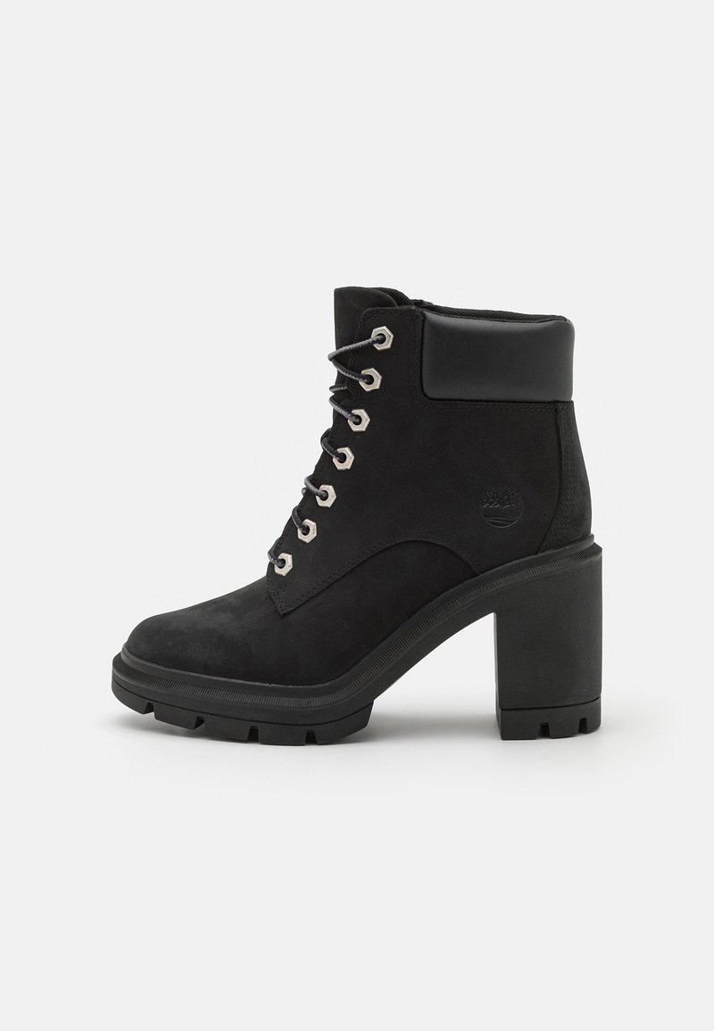 Black suede ankle boots with a chunky high heel, lace-up design, silver eyelets, and a padded collar for comfort. Rugged sole texture.