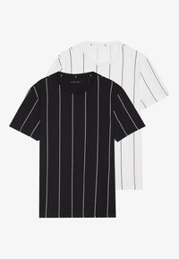 Dos camisetas de manga corta, una negra con rayas verticales blancas y una blanca con rayas verticales negras, hechas de una tela lisa.