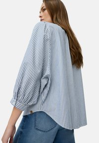 Stribet blå og hvid oversized bluse med puffede ærmer, rund kant og sideskår; lavet af letvægtsstof.