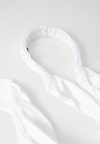 White fabric headband with a soft, gathered texture and a netted accent. It features a smooth, round shape and draped fabric ends.