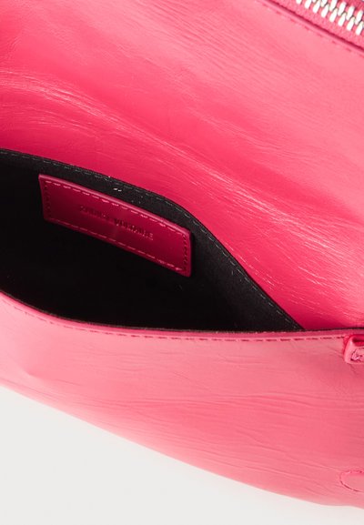 Φούξια δερμάτινη τσάντα με ανοιχτό φερμουάρ που αποκαλύπτει μαύρο εσωτερικό και μια μικρή ροζ δερμάτινη ετικέτα μέσα.