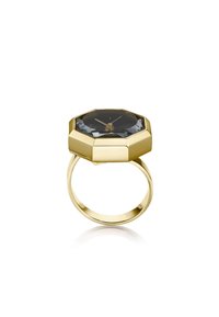 Reloj de anillo en tono dorado con una esfera octagonal. El reloj presenta un cristal negro facetado y tres agujas doradas sobre un dial oscuro.