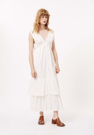 Robe midi blanche à étages avec un décolleté en V, fermeture à boutons et bordure en dentelle, fabriquée en tissu léger. Associée à des sandales à talons carrés marron.