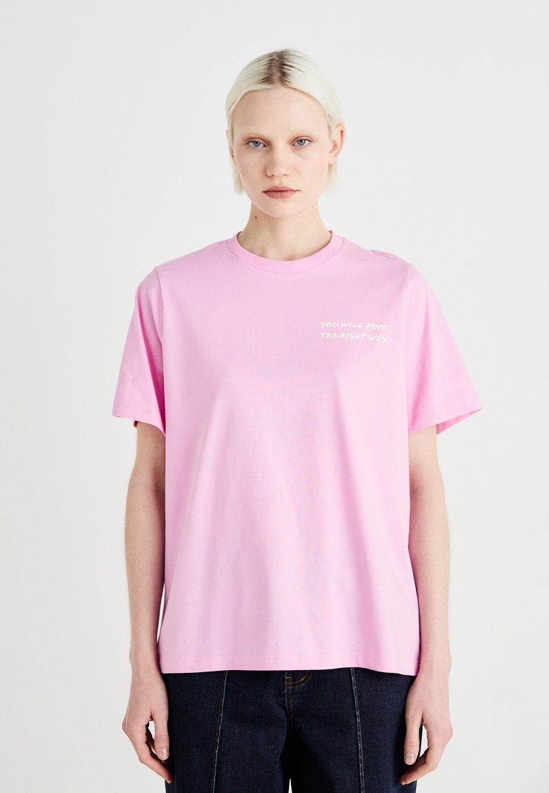 Camiseta de algodón rosa con cuello redondo y mangas cortas; presenta el texto "ENCONTRARÁS EL CAMINO CORRECTO" en blanco, ubicado en el lado izquierdo.
