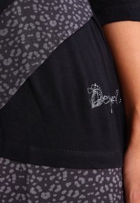 Svart topp med en strukturerad grå leopardtrycköverdrag, accentuerad med silverbroderi. Slätt tyg med korta ärmar och en figurnära passform.