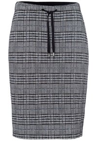 Jupe à carreaux noir et blanc avec taille à cordon, présentant un tissu texturé avec un mélange de motifs petits et grands.