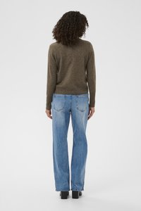 Pull marron en maille, jean bleu taille haute et chaussures noires à talons carrés. Le pull présente un col rond et des poignets ajustés, avec une texture lisse.