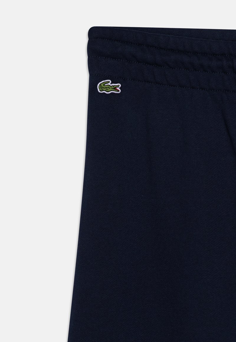 Marineblaue Jogginghosen mit elastischem Bund, ausgestattet mit einem kleinen, gestickten grünen Krokodil-Logo auf der linken Seite. Weiche Textur, lässiges Design.