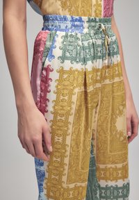 Pantalones estampados con un diseño multicolor en rosa, verde, azul y amarillo, con cintura elástica y detalle de cordón.
