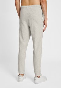 Graue Jogginghose mit schmal zulaufendem Bein, elastischem Bund und Seitentaschen. Der Stoff wirkt weich und leicht strukturiert.