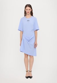 Blue and white striped dress featuring short sleeves, a relaxed fit, front draping, and embroidered logo at the chest.