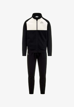 Completo sportivo nero composto da una giacca con zip e pannelli bianchi sulle spalle, abbinata a pantaloni neri, realizzati in un tessuto liscio e morbido.