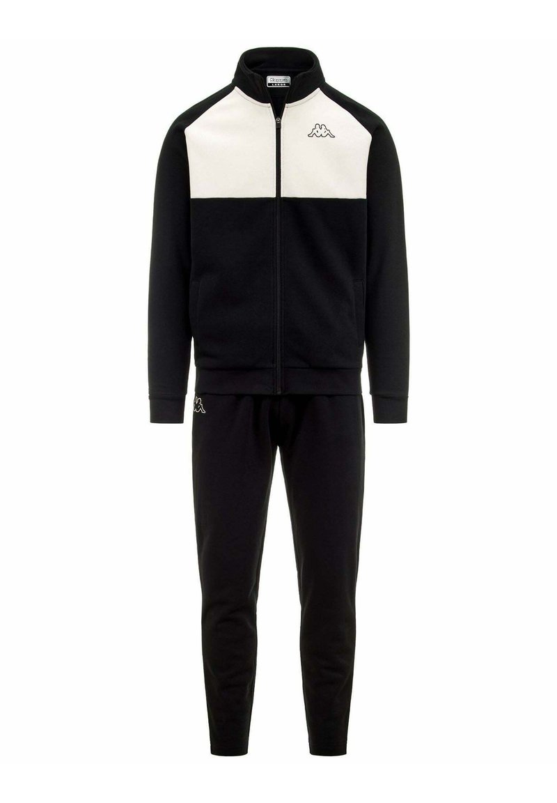 Chándal deportivo negro que incluye una chaqueta con cremallera y paneles blancos en los hombros, junto con pantalones negros a juego, fabricado en un tejido suave y liso.