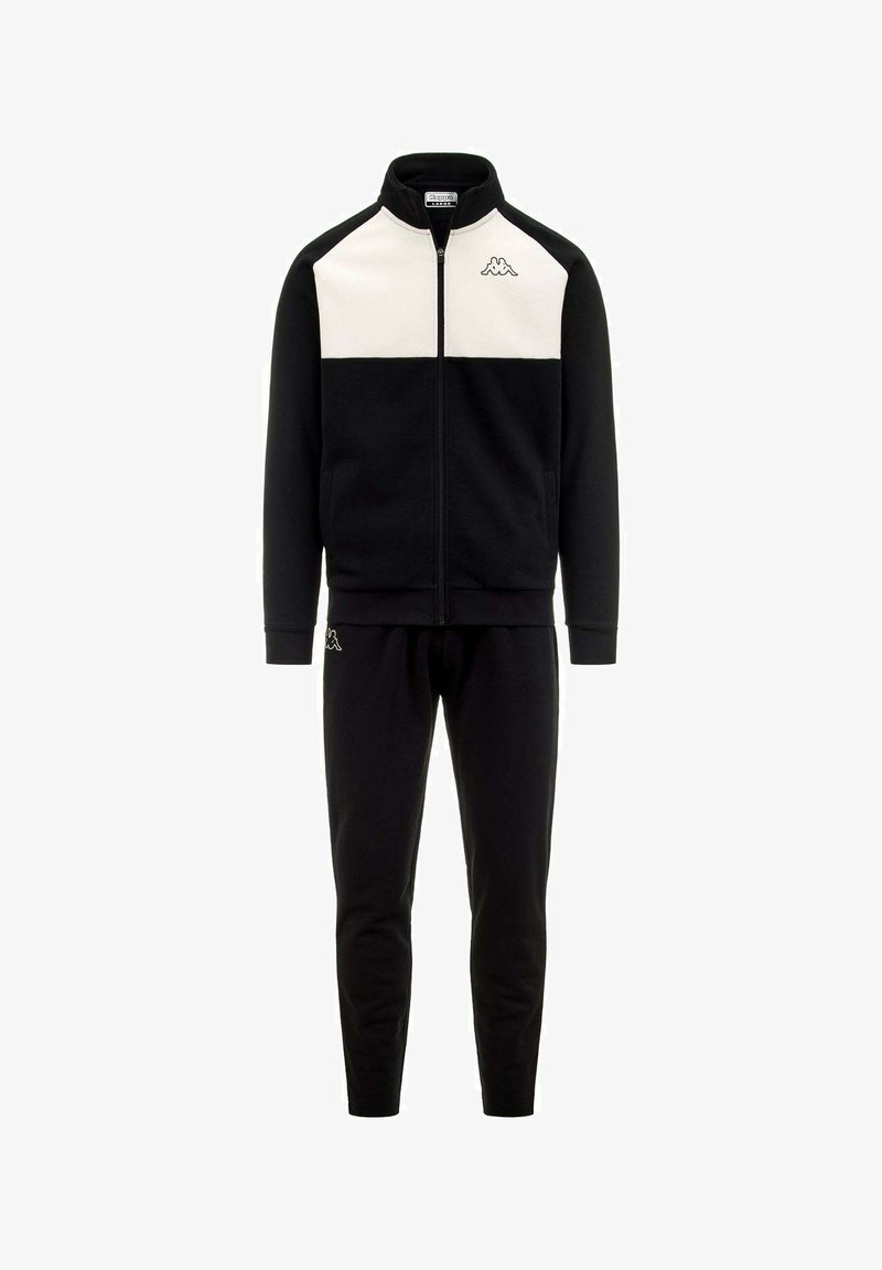 Chándal deportivo negro que incluye una chaqueta con cremallera y paneles blancos en los hombros, junto con pantalones negros a juego, fabricado en un tejido suave y liso.