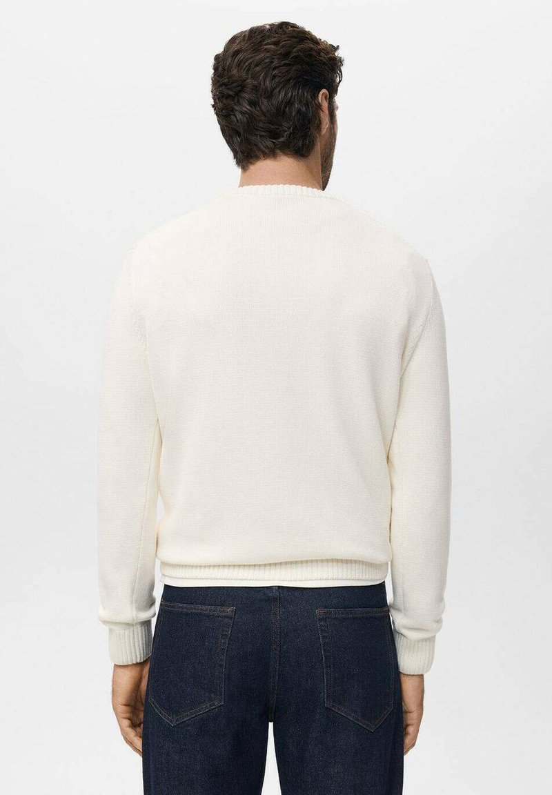 Crewneck-Pullover aus weichem, cremefarbenem Strickmaterial. Rippstrickbündchen und -saum, schlichtes Design, abgebildet an einer Person, die dunkle Jeans trägt.