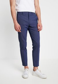 Marinblå skräddarsydda byxor med en texturerad tyg, slim fit, framfickor och en slät midja, i kombination med vita sneakers.