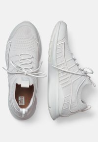 Weiße Sportschuhe mit einem strukturierten Strick-Obermaterial, Schnürung, gepolstertem Kragen und einer flexiblen Gummisohle. Verstärkungen an Zehen- und Fersenbereich.