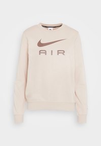 Ljusbeige Nike sweatshirt med rund halsringning, långa ärmar och en framträdande brun "AIR"-logotyp på framsidan. Mjuk, strukturerad tyg.