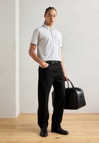 Hellgraues Poloshirt mit schwarzem Rand, schwarze Hose, schwarer Gürtel und schwarze Tasche. Glatte Textur, entspannte Passform, modernes Design.