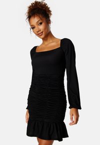 Czarna dopasowana sukienka z kwadratowym dekoltem, długimi rękawami, marszczoną strukturą i rozkloszowanym dołem. Miękki, elastyczny materiał.