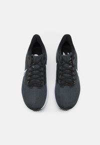 Czarne buty sportowe z teksturowanym siateczkowym wierzchem, zaokrąglonym czubkiem, sznurówką i białą podeszwą. Posiadają czarne sznurowadła oraz akcenty z logo.
