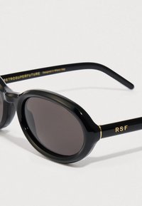 Óculos de sol ovais pretos com lentes escuras, armação de plástico brilhante e detalhes em dourado, apresentando a marca "RSF" na lateral.