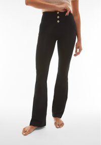 Pantalones negros de cintura alta con un corte ajustado y pierna acampanada, que presentan tres botones dorados en la cintura y dos bolsillos frontales. Textura suave.