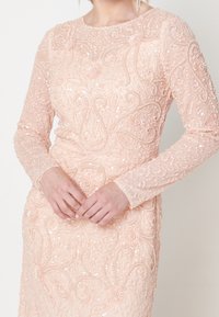 Vestito pesca a manica lunga decorato con perline e paillettes intricate, caratterizzato da un motivo floreale e da una scollatura rotonda.