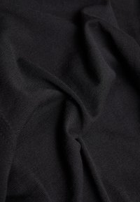 Schwarzer Strickstoff, der in Falten präsentiert wird, mit einer weichen Textur und gleichmäßigem Webmuster. Glatte Oberfläche ohne sichtbare Muster oder Akzente.