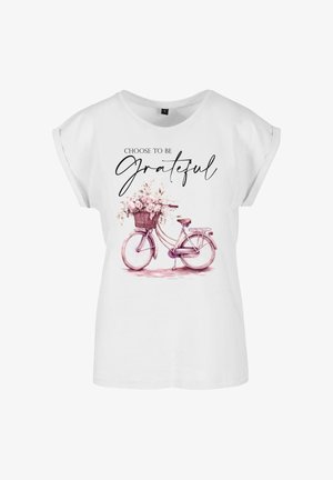 Valge lühikeste varrukatega T-särk, millel on roosa jalgrattagrafika lillekorvi ja tekstiga "Vali olla tänulik" selle kohal.