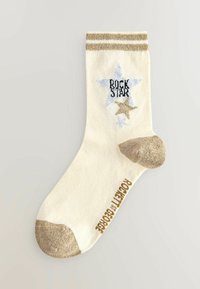 Cremefarbene Socke mit goldenen Akzenten, versehen mit einem blauen Stern und dem Text "ROCK STAR". Goldene Zehen- und Fersenpartie, gerippter Bund. Strukturmaterial.