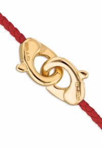 Cierre de tono dorado entrelazado con cuero trenzado rojo. Superficie metálica lisa con bordes redondeados y acabado brillante. Trenza roja texturizada.