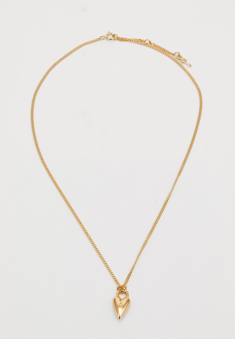 Kuldne kaelakett, millel on südamekujuline ripats. Ripatsil on sile ja läikiv pind, millel on väike lukutasku detail.