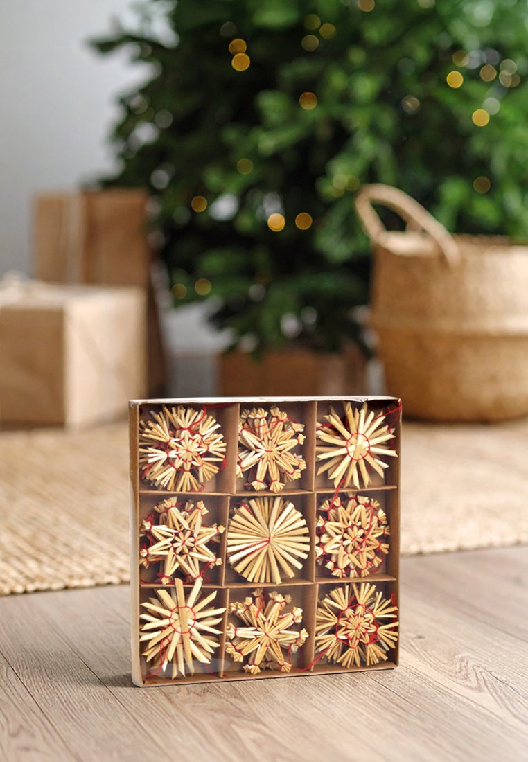 Neun handgefertigte Strohdeko in einer quadratischen Box angeordnet, mit kunstvollen Stern- und Kreis-Mustern, roten Akzenten auf einem neutralen Hintergrund.