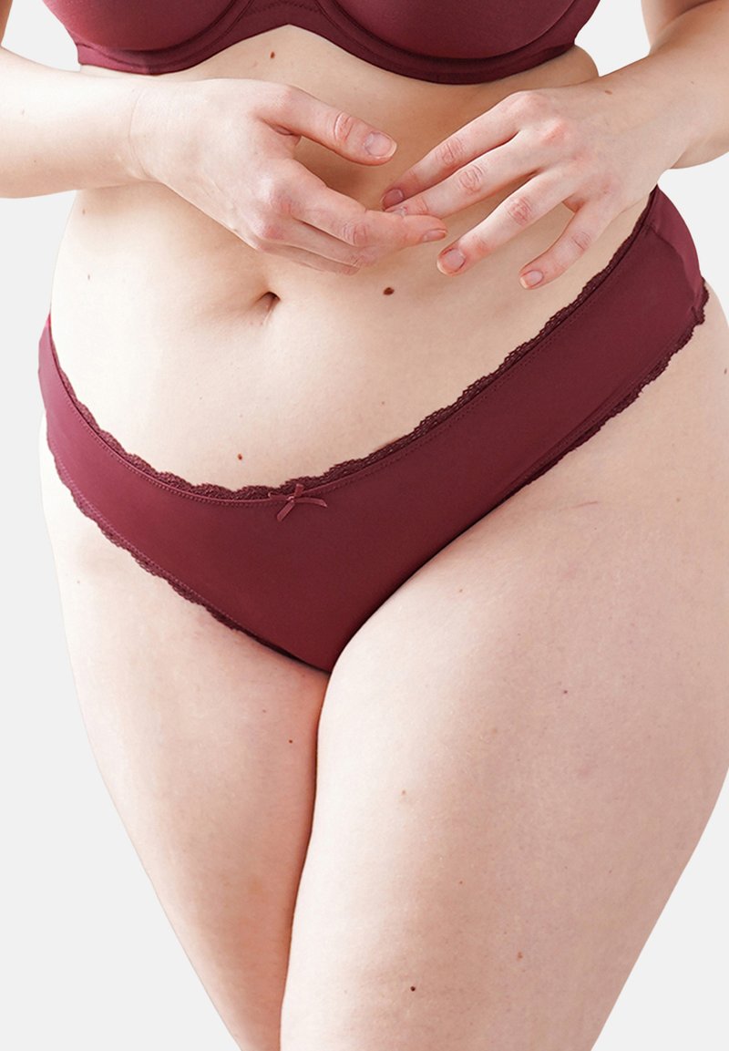 Burgunder Unterwäsche mit Spitzenbesatz, die eine weiche Textur und eine Schleifenakzentuierung an der Vorderseite aufweist. Formschön für einen bequemen Sitz an Taille und Hüften.