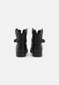 Bottines en cuir noir avec un bout arrondi, des languettes au dos et des sangles sur les côtés. Texture lisse et un talon bas solide.
