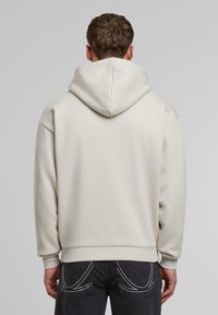 Hettegenser i lys beige, myk stoff, avslappet passform. Utmerkede detaljer inkluderer ribbestrikkede mansjetter og kant, med et enkelt design.
