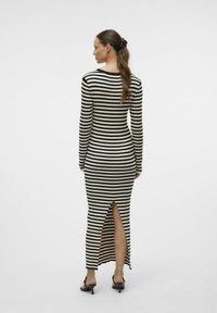 Robe à manches longues à rayures noires et blanches, avec une fente sur le côté, design ajusté et col rond. Texture douce avec un léger élastique.