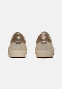 Sneakers in pelle beige con dettagli metallici dorati sul tallone e una fodera testurizzata. Design minimalista con cuciture rinforzate e suola in gomma.