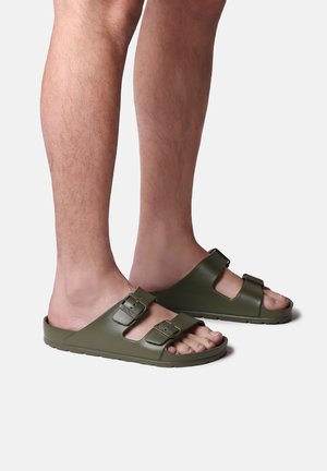 Sandales vert olive à double boucle, en matériau plastique lisse ; design ouvert à l'avant ; semelle texturée pour une meilleure adhérence.
