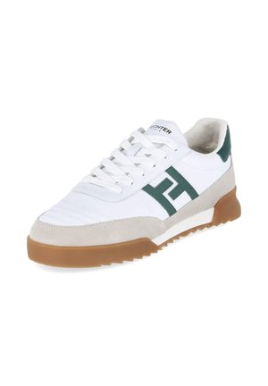 Weißer Sneaker mit beigen Wildleder-Akzenten, grünem Seitenlogo, brauner Gummisohle und weißen Schnürsenkeln, fotografiert vor weißem Hintergrund.