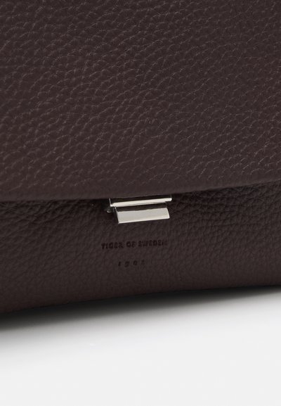 Σκούρο καφέ δερμάτινη τσάντα συμπλέκτη με υφή πετραδιού, που διαθέτει ασημένιο κούμπωμα και ανάγλυφο λογότυπο στη βάση. Κομψός, μινιμαλιστικός σχεδιασμός.