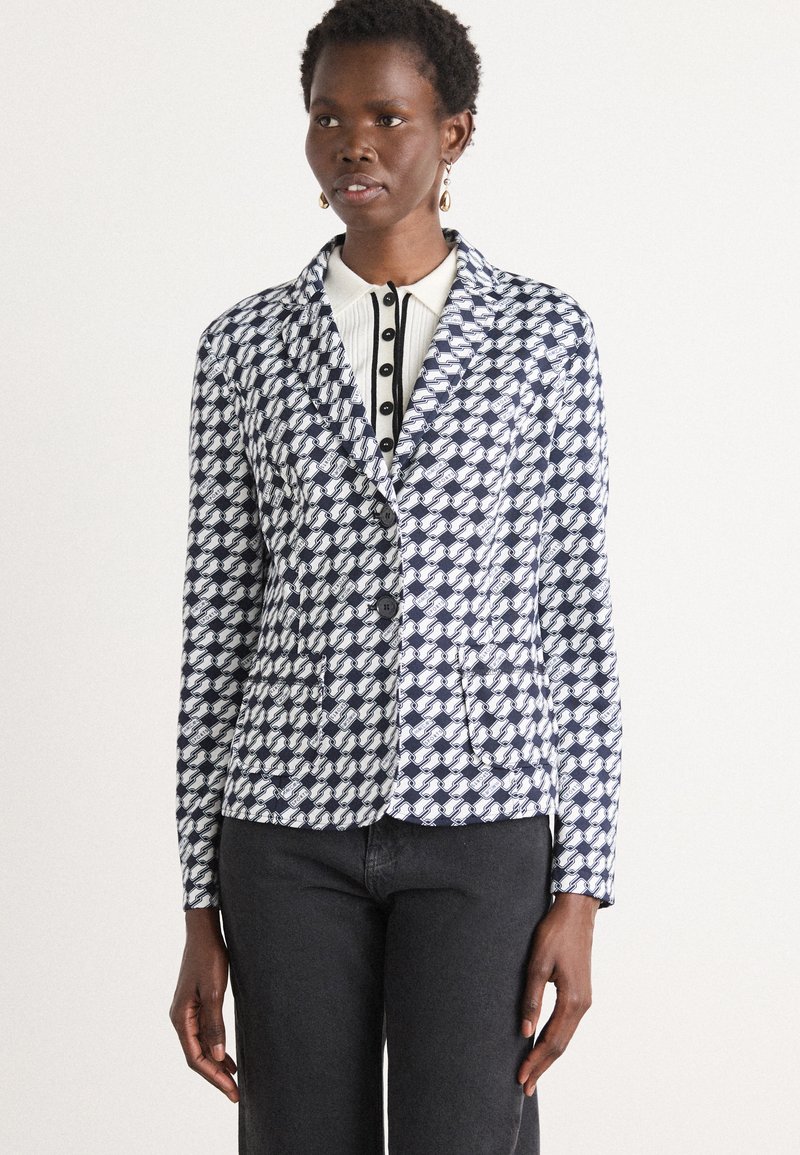 Blazer in un motivo geometrico blu navy e bianco, con chiusura a un bottone, colletto a revers e due tasche frontali. Il tessuto ha una superficie liscia.