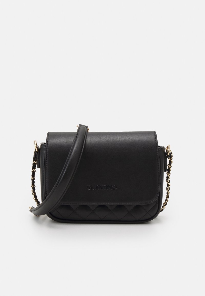 Černá kožená taška přes rameno s prošívaným vzorem na spodní části, zlatým řetízkovým popruhem, magnetickým zapínáním na klapku a vyraženým logem na přední straně.
