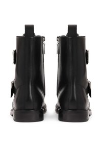 Botines de cuero negro con un diseño elegante, cremalleras traseras y detalles de hebilla ajustables. Textura suave y tacones bajos.