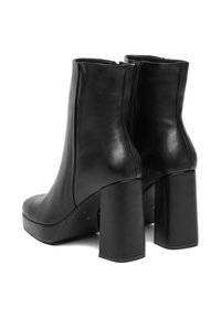 Czarne skórzane botki za kostkę o gładkiej fakturze, z kwadratowymi wysokimi obcasami i bocznym zamkiem. Posiadają platformę dla zwiększonej wysokości.