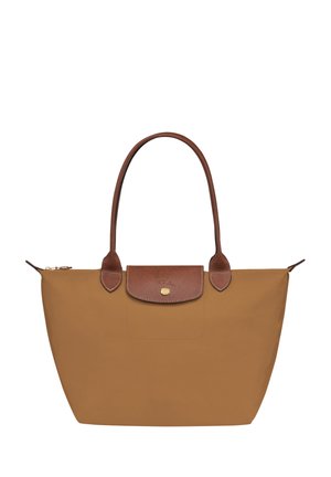 Tan nylon tote bag with brown leather accents, featuring a zip closure, two shoulder straps, and a flat base. Gold logo on front flap.