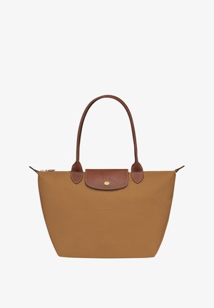 Tan nylon tote bag with brown leather accents, featuring a zip closure, two shoulder straps, and a flat base. Gold logo on front flap.