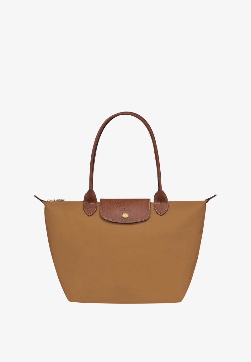 Tan nylon tote bag with brown leather accents, featuring a zip closure, two shoulder straps, and a flat base. Gold logo on front flap.